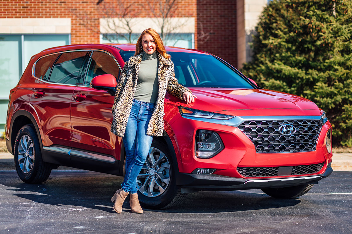 Woman posing in front of a car